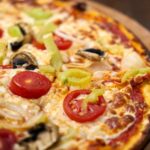Pizza mit Schinken, Pilzen und Mais belegen